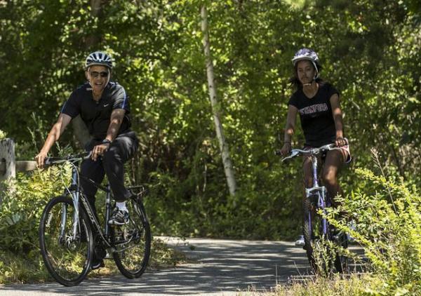 U.S. President Barack Obama cycles with his daughter Malia during their family vacation at Martha's Vineyard in Massachusetts August 15, 2014. REUTERS/Kevin Lamarque (UNITED STATES - Tags: POLITICS)