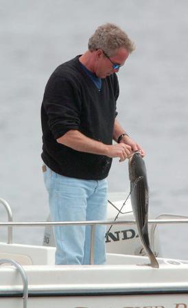 US President George W. Bush unhooks a fish off the coast of Kennebunk, ME near the family vacation home 14 June, 2003.   EPA-PHOTO/EPA/CJ GUNTHER
