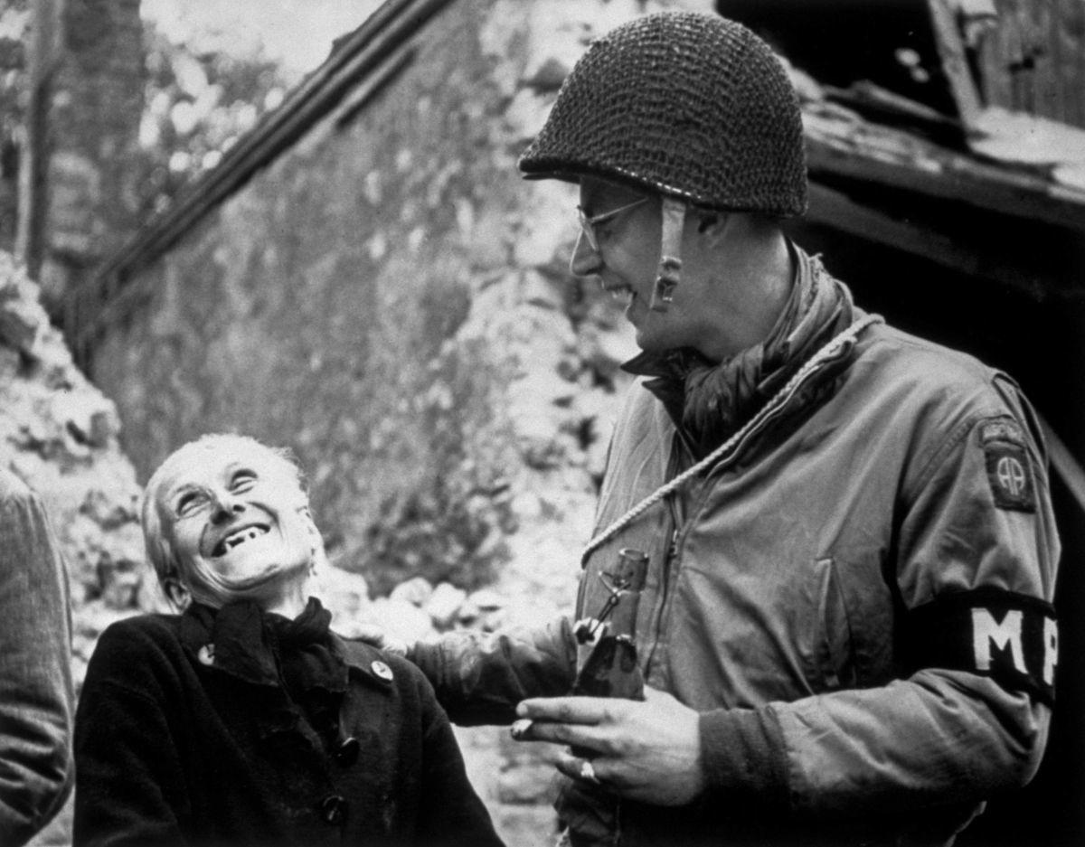 A French woman and an American paratrooper share a moment of laughter in Normandy, France. The MP was part of the U.S. Army's 82nd Airborne division that helped liberate the town of Sainte-Mère-Église.