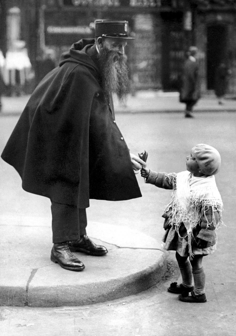 This little girl giving a police officer lilies in 1920 Paris, France. 