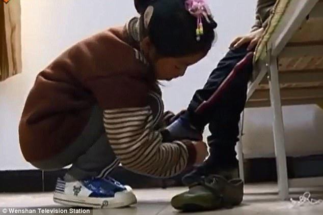 Sibling bond: The girl, from China, helps her brother get dressed before setting out to school