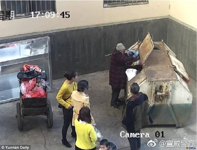 An elderly woman removes the baby girl from the bin and takes her to the hospital