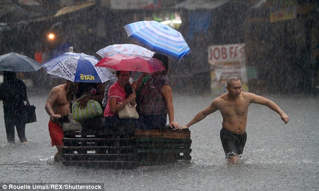 Residents of Manila use a wooden crate to move through the flooded street during heavy rainfall in the seasonal monsoon