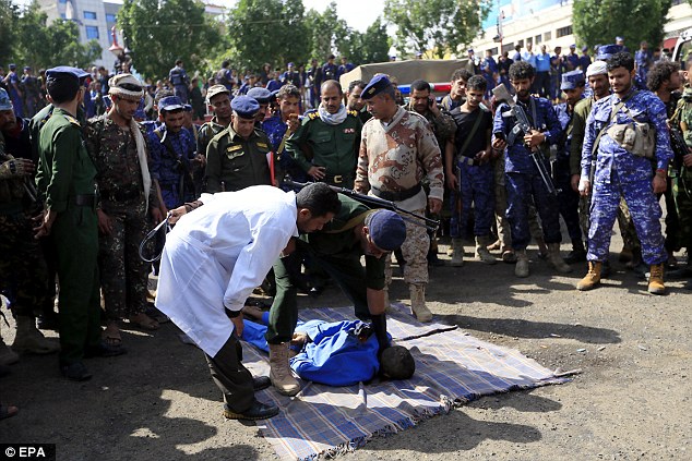 A Yemeni doctor looks on as a police officer prepare to shoot a man after he was convicted of raping and murdering a ten-year old boy