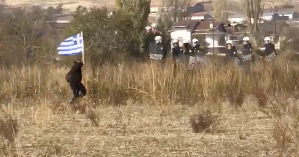 H ΕΛ.ΑΣ προσπαθεί να κλείσει τον δρόμο σε άντρα με την ελληνική σημαία κι εκείνος τους γλεντάει