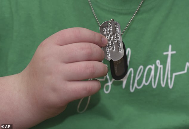 Kaleb wears a dog tag, in memory of his best friend Kenneth "K.J." Singleton, The 12-year-old Michigan boy is working odd jobs to raise money for a gravestone for Singleton