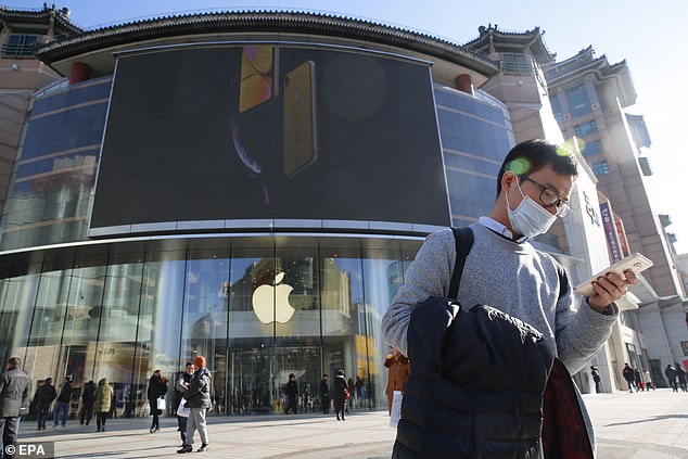 Apple products were once the most desirable electronic gadgets in China, but were priced beyond the reach of many.Â  Pictured, a man uses his phone outside an Apple store in Beijing